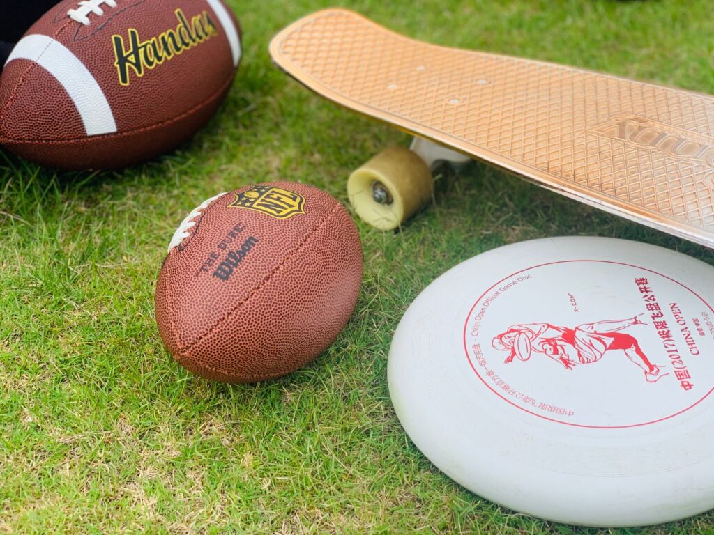 aerospace A close-up of sports equipment including a football, skateboard, and frisbee on grass.