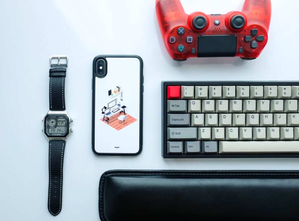 oil-1 Top view of modern gadgets including a smartphone, watch, game controller, and keyboard.