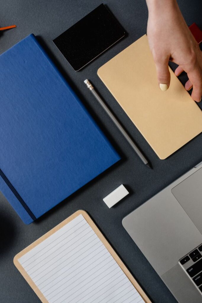 aerospace Top view of an organized desk with hand, notebooks, stationery, and laptop, perfect for office themes.